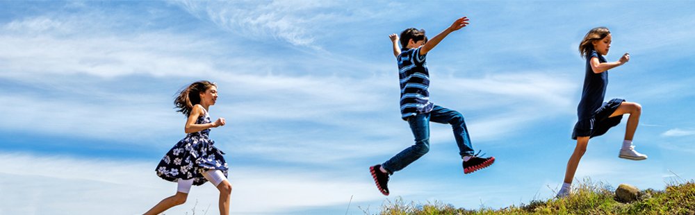 Kinder rennen fröhlich über eine Wiese: Hier macht Kindsein Freude und wird gefördert, dank qualifiziert ausgebildeter Erzieherinnen und Erzieher an den Evangelischen Fachschulen für Sozialpädagogik.