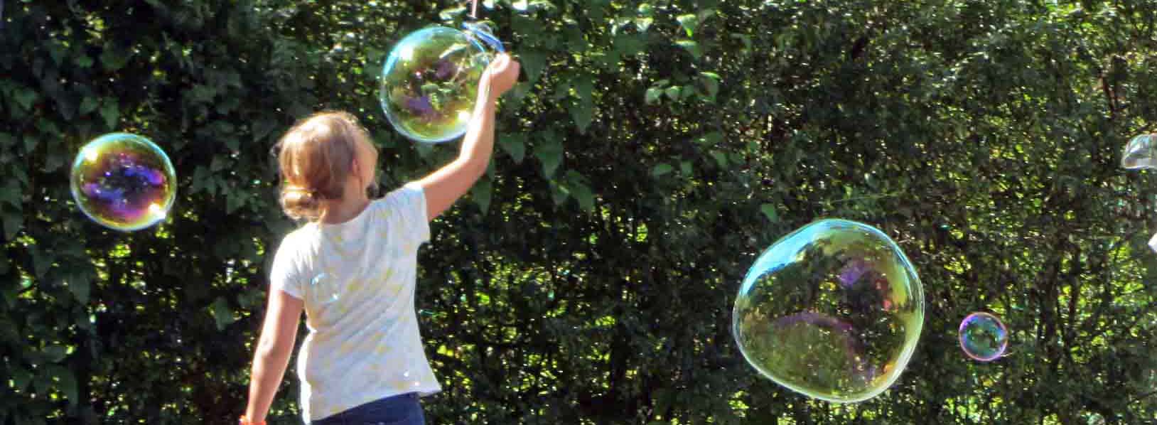 Ein Mädchen lässt riesengroße Seifenblasen entstehen. Bewegung und Experimentierfreudigkeit gehört zur Ausbildung an den Evangelischen Fachschulen für Sozialpädagogik. Wir bilden Erzieherinnen und Erzieher aus. 